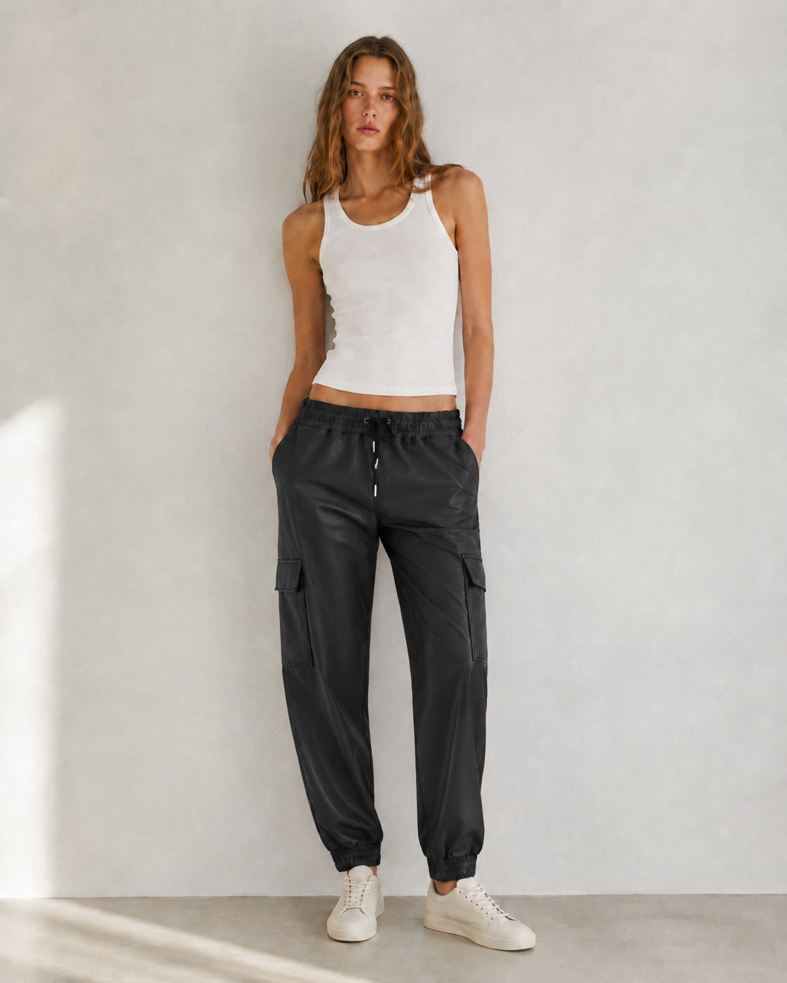 Model draagt zwarte lederlook Cargo Broek Nova met elastische taille en cargozakken