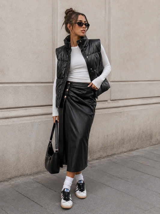 Model draagt zwarte lederlook Rok Celeste met zijsplit en goudkleurige knopen